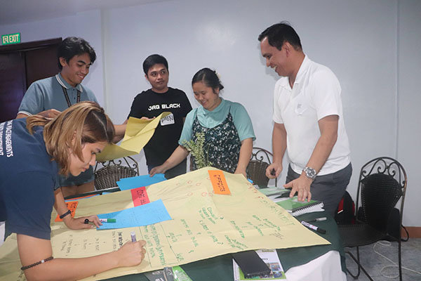 Participants working at a table with manila and colored paper for a activity